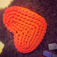 an orange crocheted hat laying on top of a black furry animal's head