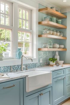 a kitchen with blue cabinets and open shelving above the sink is pictured in this image