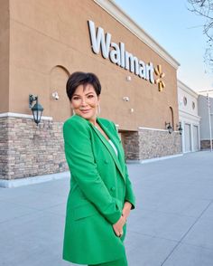 a woman standing in front of a walmart store wearing a green suit and heels