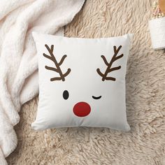 a white pillow with reindeer's face on it sitting on top of a bed