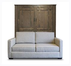 a white couch sitting in front of a wooden wall with two doors on each side