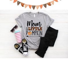 Mom of the little Pumpkin birthday shirt! We love this orange plaid print paired with the super cute patch print pumpkin - so cute for a fall theme birthday! We do have a matching one for Dad and the Birthday child in our shop. Every tee is handmade to order with love. Printed on our Unisex Adult Tees, these do run large. For a women's fit, we do suggest sizing down. For a looser fit, size as you would normally purchase. Please note since all tees are handmade, graphic placement may vary slightl Cute Name Print Tops For Fall, Birthday Cotton Shirt With Funny Print, Cute Tops With Name Print For Fall, Cute Orange Cotton Shirt, Graphic Print Tops For Birthday In Fall, Fall Cotton T-shirt With Name Print, Cotton T-shirt With Name Print For Fall, Cute Fall Birthday Tops, Fun Cotton Shirt For Mother's Day