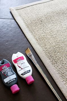 two different colored toothpaste next to a brush on a wooden table with a piece of fabric in the background