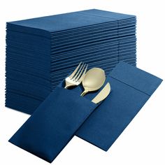 a stack of blue napkins with gold forks and knives on top of them next to a pile of silverware