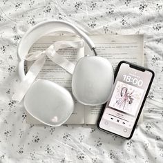 headphones and an mp3 player are laying on a bed next to a cell phone