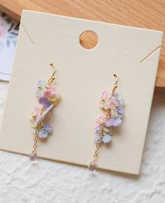 a pair of earrings with flowers hanging from it's earwires on top of a card board