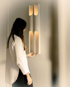 a woman standing in front of a wall light