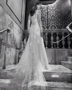 a woman in a wedding dress standing on some stairs with her back to the camera