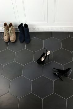 three pairs of shoes sitting on the floor in front of a white door with hexagonal tiles