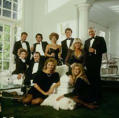 a group of people dressed in formal wear posing for a photo with a dog on the floor