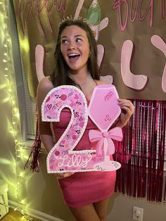 a woman holding up a pink number two sign in front of a happy birthday banner