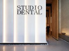 the entrance to studio dental with a woman walking through it and an illuminated sign on the wall