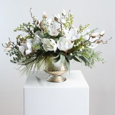 a vase with white flowers and greenery in it