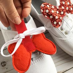 someone is holding up a pair of shoes with red and white bows on them,