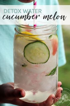 a person holding a mason jar filled with cucumber melon and lemonade