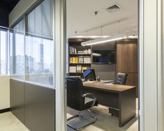 an office with a desk, chair and bookshelf in the middle of it