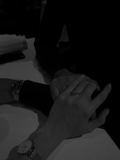 two people are sitting at a table with their hands on each other's wrist