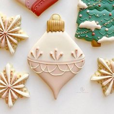 decorated cookies are arranged in the shape of christmas trees and snowflakes on a white surface