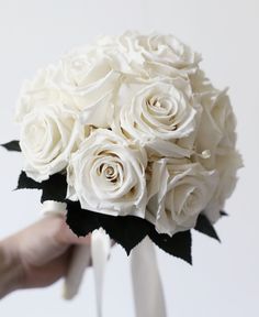 a bouquet of white roses being held by someone