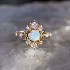 an opalite and diamond ring sits on top of a rock, surrounded by small white stones