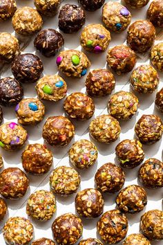 several different types of chocolate balls on a white surface with colorful sprinkles