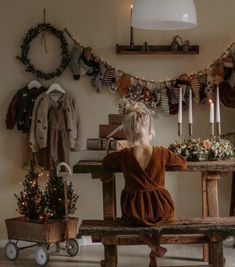 a woman sitting on a bench in front of a table with candles and wreaths