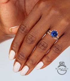 a woman's hand with white nails and a blue stone ring on her finger