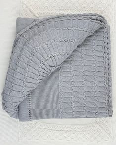 a gray blanket is folded on top of a white doily