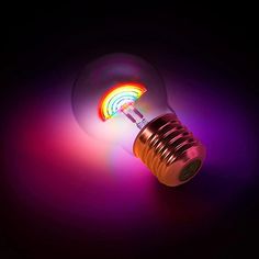 a colorful light bulb sitting on top of a black table next to a rainbow colored object