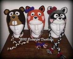 three knitted animal hats on top of a wooden table next to two other headpieces