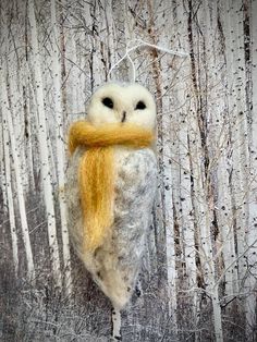 an owl with a yellow scarf hanging from it's back in front of some trees