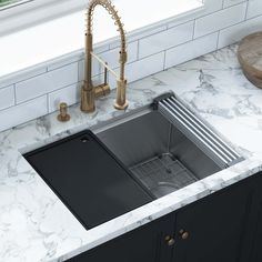 a kitchen sink under a faucet in a marble counter top with gold faucets