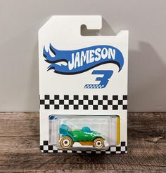 a green toy car sitting on top of a wooden table next to a white box