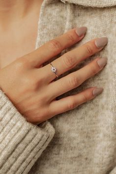 a woman's hand with a ring on her left wrist, wearing a sweater