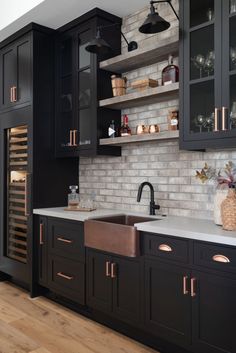 a kitchen with black cabinets and white counter tops, an open wine rack in the corner