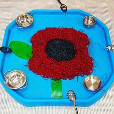 a blue tray with a flower made out of noodles and silver dishes on it,