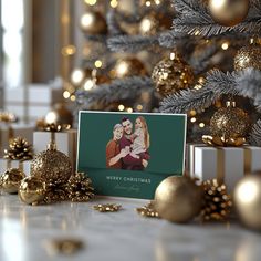 a christmas card sitting on top of a table next to gold ornaments and a tree