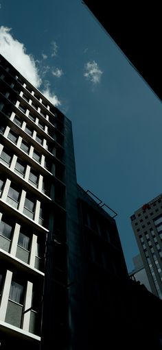 a tall building with windows and balconies against a blue sky filled with clouds