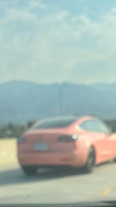 a pink car is driving down the highway