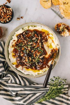 mashed potatoes topped with gravy and chopped pecans in a bowl next to other dishes