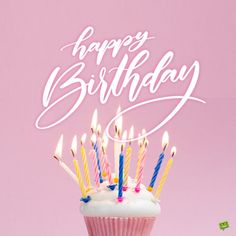 a cupcake with white frosting and multi - colored candles is shown in front of a pink background