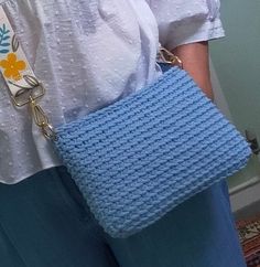 a close up of a person holding a blue purse with a chain attached to it