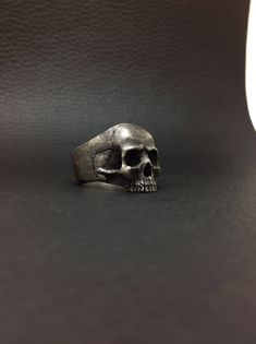 NEW Anatomical Design Keith skull Ring. Textured, rough, aged and blackened finish. Made of 925 sterling silver. Approximate weight: between 20 and 25 grams depending on size.  Measures: Height: 21 mm (seen from the front) Width: 23 mm (seen from the front). This measure varies according to the size. Band width: It starts at 11 mm, decreases to 8.5 mm in the less wide area and grows back to 11 mm ALL SIZES AVAILABLES.... JUST TELL ME THE SIZE YOU NEED. If you have any questions please send me an Hand Cast Black Skull Ring, Black Hand Cast Skull Ring Gift, Black Hand Cast Skull Ring, Vintage Black Skull Ring, Handmade Vintage Black Skull Ring, Collectible Symbolic Black Skull Ring, Keith Richards, Exclusive Jewelry, Skull Ring