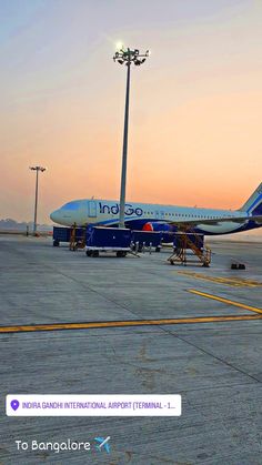 an airplane is parked on the tarmac at sunset