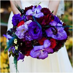 a bride holding a bouquet of purple and red flowers