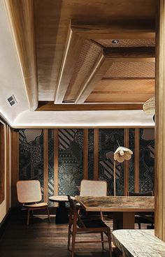 a wooden table and two chairs in front of a wall with intricate designs on it