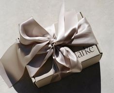 an open box with a white bow on the top that says arke in it