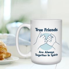 a white coffee mug sitting on top of a table next to a plate of food