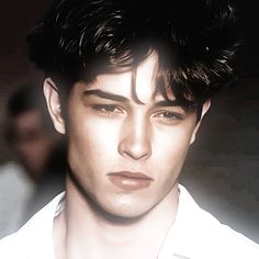 a close up of a person wearing a white shirt and looking at the camera with an intense look on his face