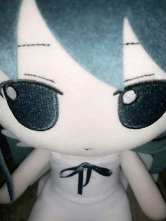 a close up of a stuffed animal doll with blue hair and eyes, wearing a white dress